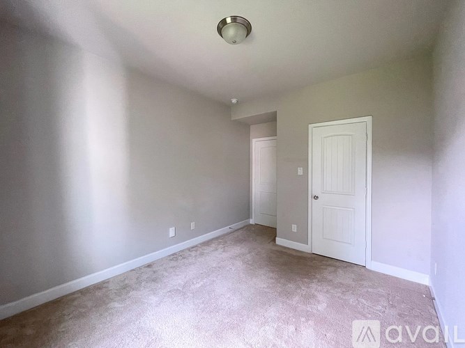 A room with a carpeted floor and a white door.