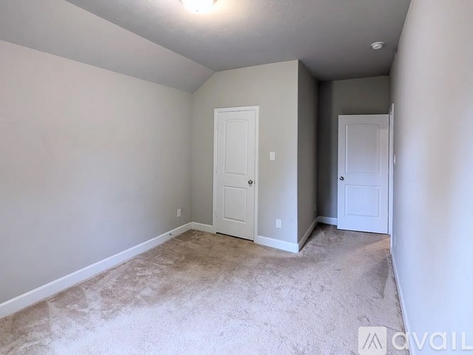 A room with a carpeted floor and two white doors.