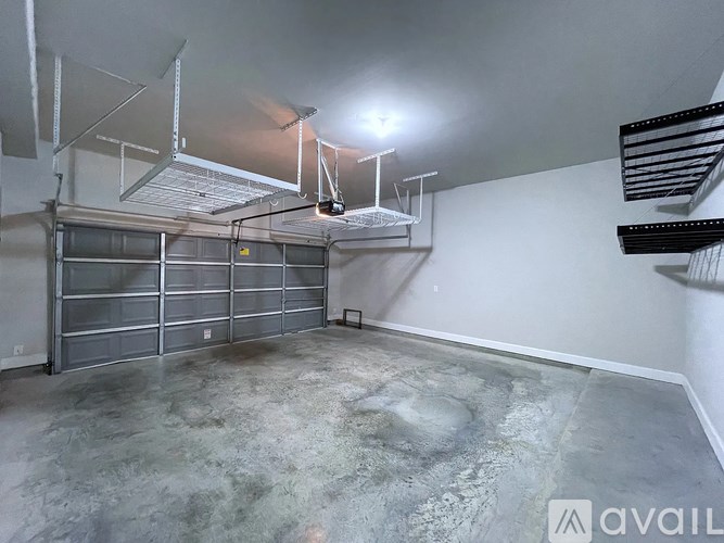 A large empty garage with a concrete floor and a metal shelving unit.