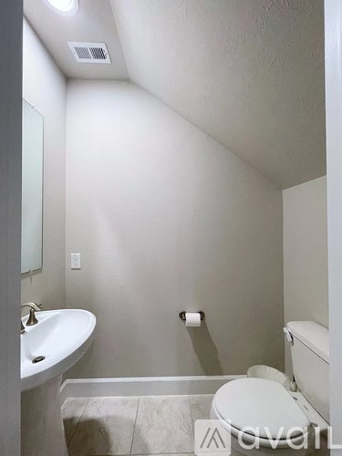 A white toilet is in a bathroom with a sink and a mirror.