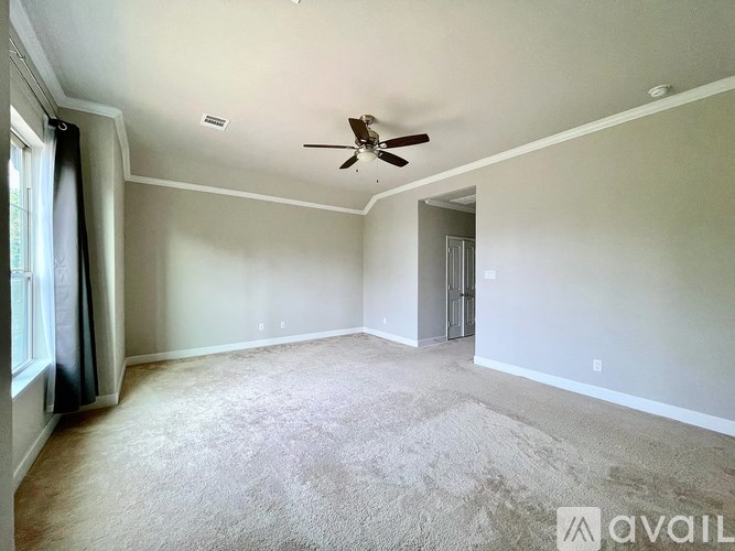 A spacious room with a ceiling fan and carpeted floor.