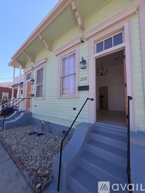 A house with a green exterior and a staircase leading to the front door.