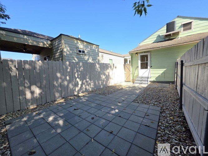 A backyard with a paved walkway and a fence.