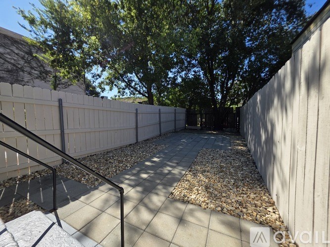A backyard with a gravel path and a metal railing.