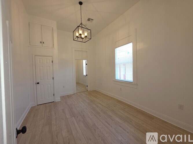 A room with wooden flooring and a chandelier hanging from the ceiling.