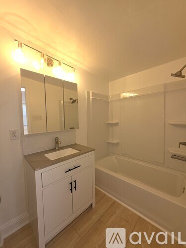 A bathroom with a white tub, sink, and cabinets.