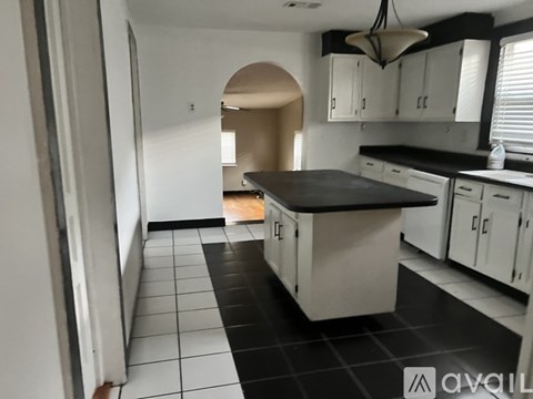 A kitchen with white cabinets and black countertops.