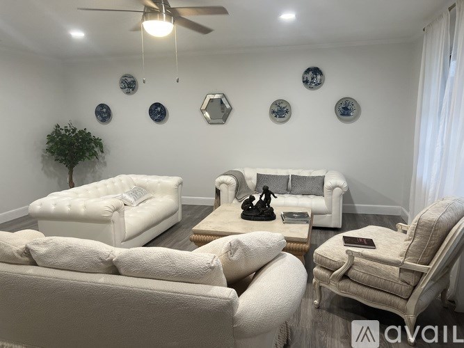 A living room with white furniture and decorations on the wall.