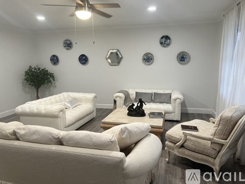 A living room with white furniture and decorations on the wall.