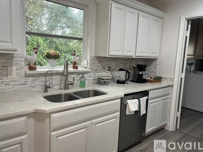 A kitchen with white cabinets and a black dishwasher.