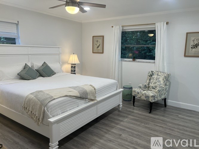 A bedroom with a bed, chair, and window.