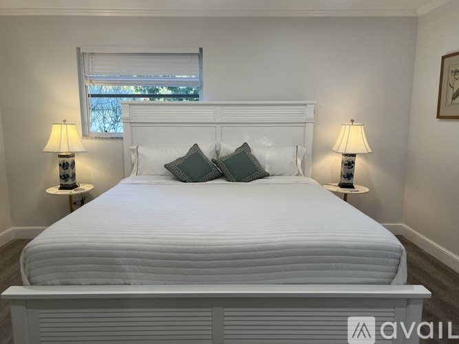 A white bed with a white headboard and two pillows is in the center of the room.