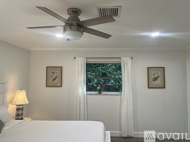 A bedroom with a white bed and a ceiling fan.