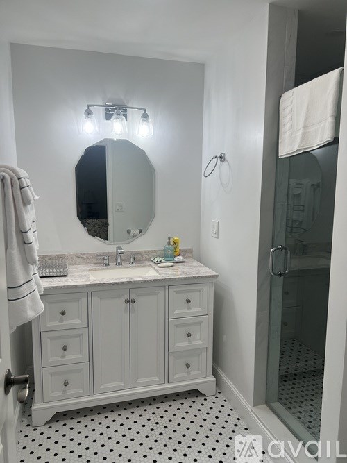 A bathroom with a white cabinet and a mirror above it.