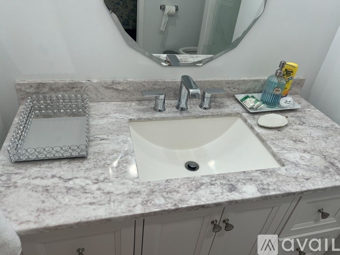 A bathroom sink with a marble countertop and a mirror above it.