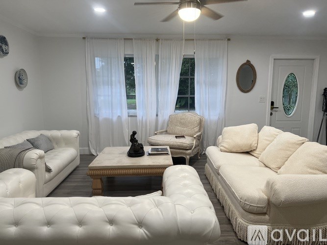 A living room with white furniture and a ceiling fan.