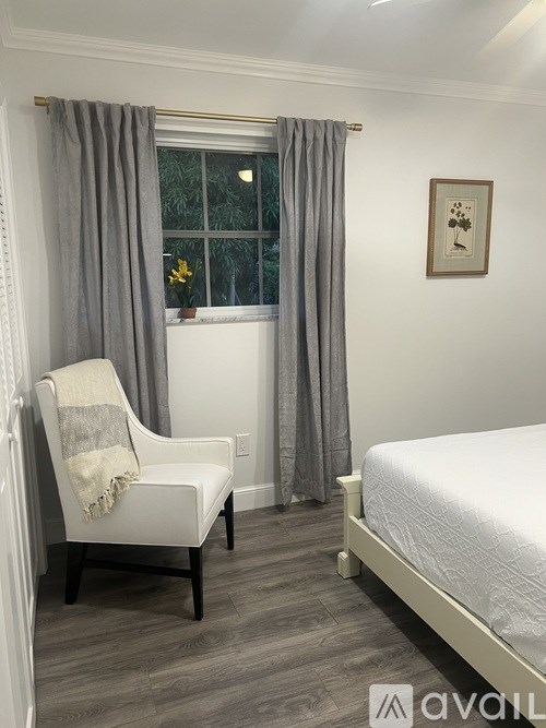 A bedroom with a bed, chair, and window.