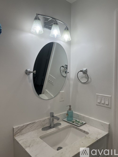 A bathroom with a marble countertop and a round mirror.