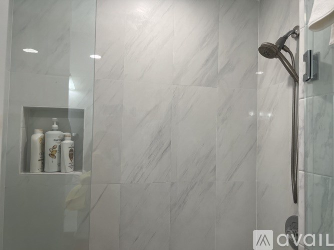 A shower area with a glass door and a glass shower head.