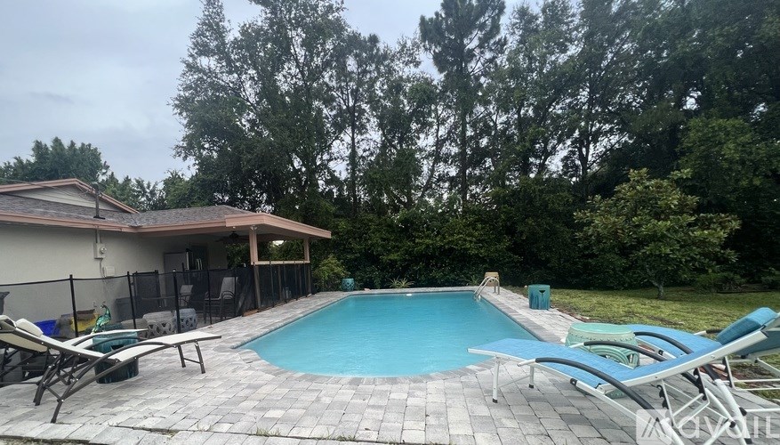 A pool surrounded by trees and a house.