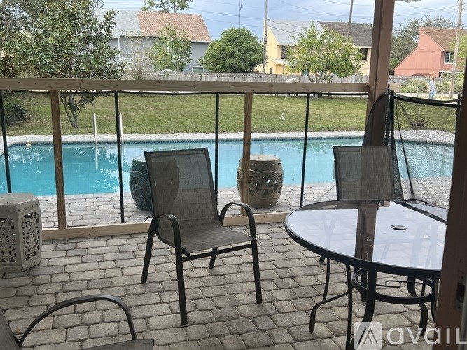 A patio with a table and chairs overlooking a pool.