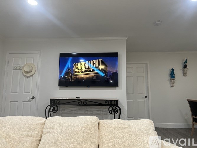 A living room with a television on the wall and a couch in front of it.