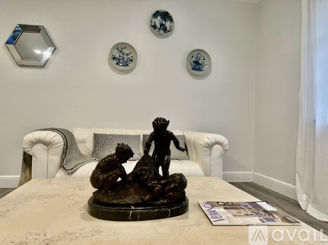 A room with a white sofa and a statue of two people on a table.