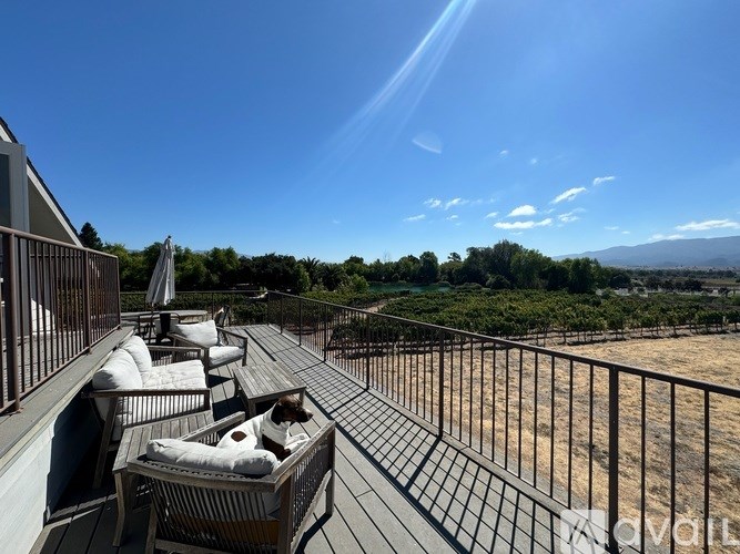 A balcony with chairs and a table overlooking a landscape.