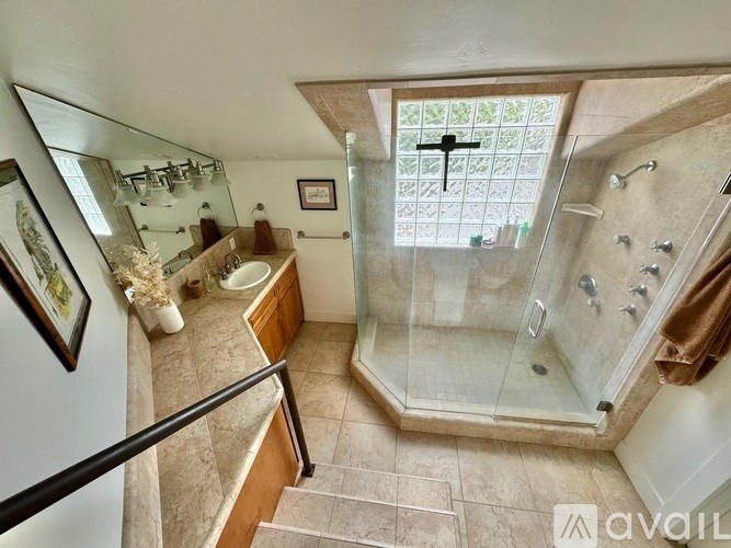 A bathroom with a glass shower stall and a sink.