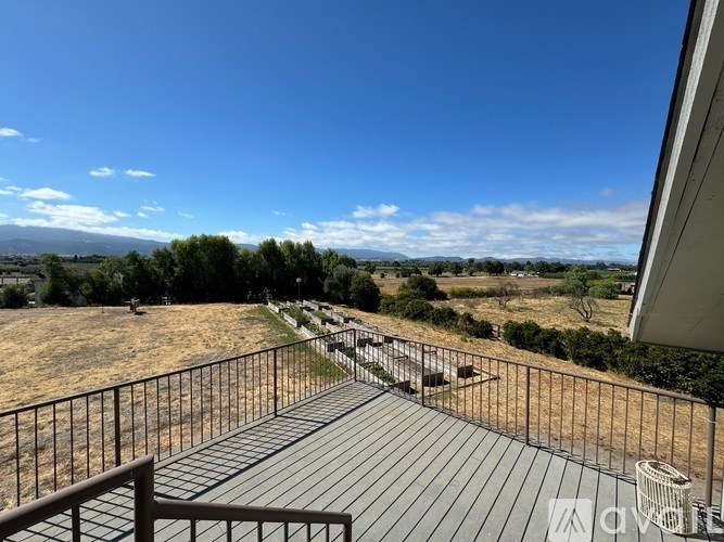 A balcony with a metal railing overlooks a field.