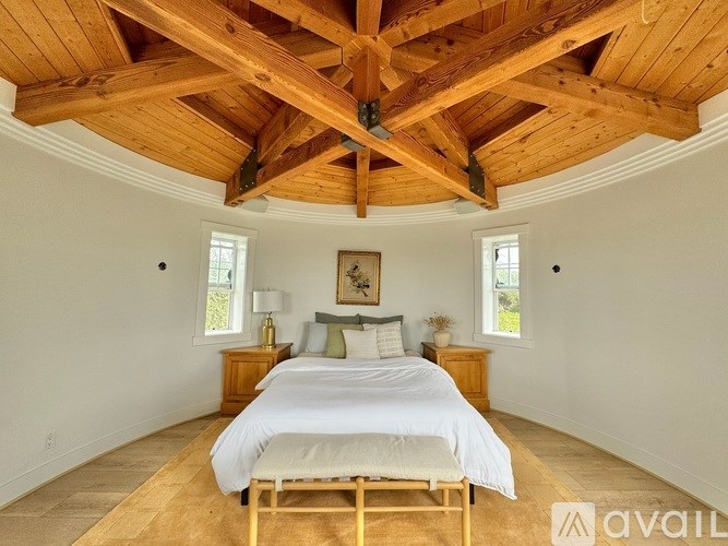 A bedroom with a large bed and wooden beams on the ceiling.