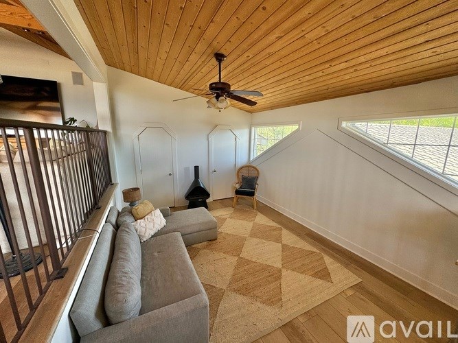 A living room with a couch, rug, and a fan.