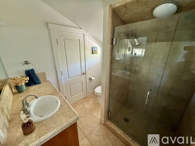 A bathroom with a sink, mirror, and shower.