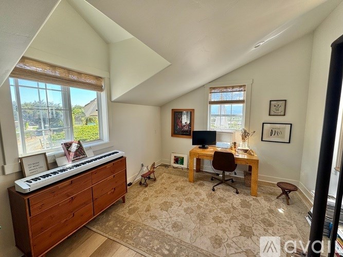 A room with a piano, a desk with a computer, and a chair.
