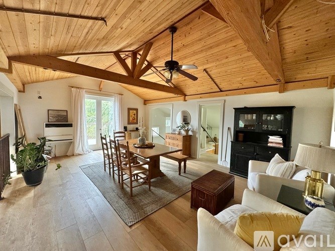 A living room with a wooden ceiling and a fireplace.