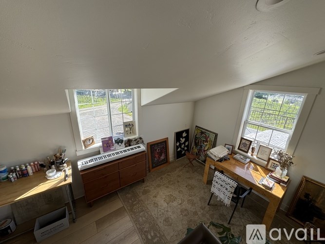 A room with a desk, chair, and a window with a view of a fence and trees.