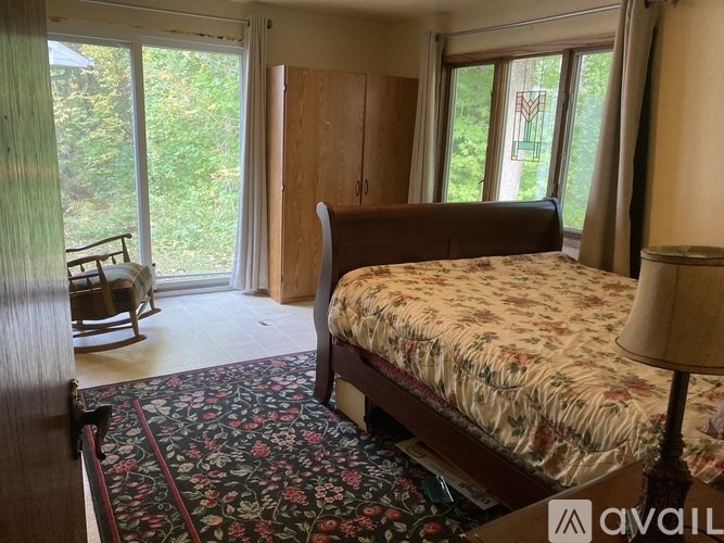 A bedroom with a large bed and a chair by the window.