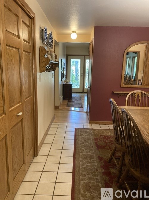 A hallway with a wooden door and a mirror on the wall.