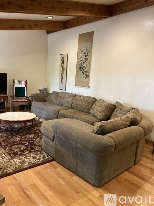 A living room with a grey sectional sofa and a round wooden table.