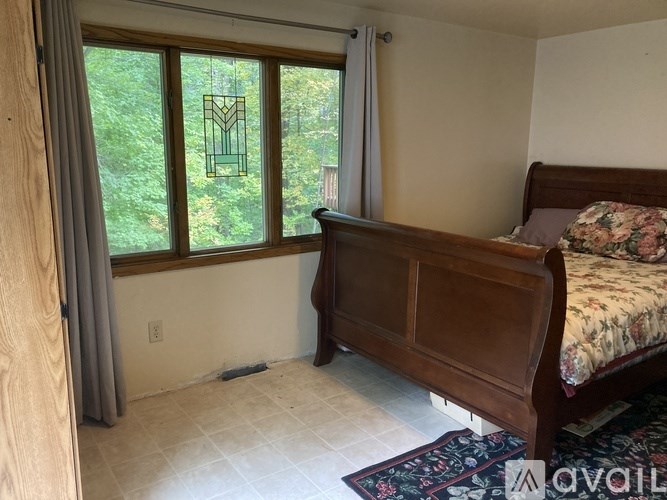 A bedroom with a large bed and a window with a view of trees.