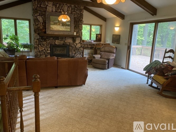 A living room with a stone fireplace and a painting above it.