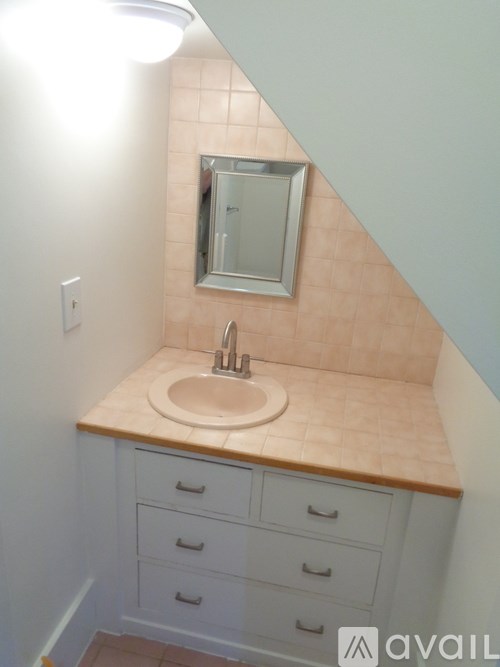 A bathroom with a sink, mirror, and drawers.