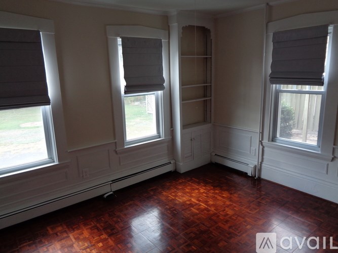 A room with wooden floors and three windows.