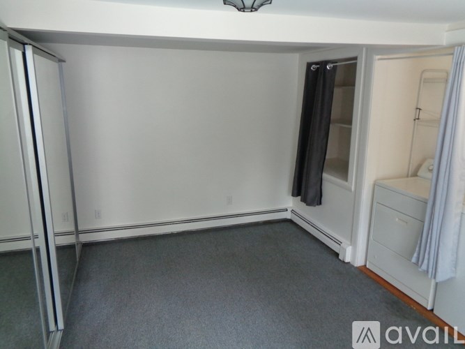 A bedroom with a white door and a grey carpet.