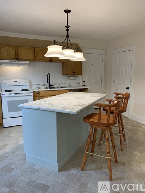 A kitchen with a white stove and wooden chairs.