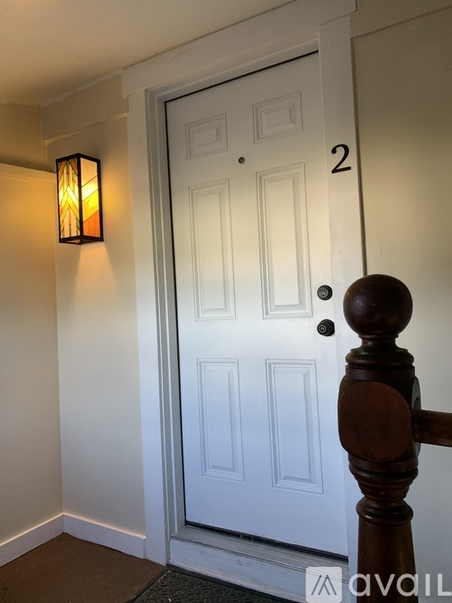 A white door with a black handle and a wooden post to the right.