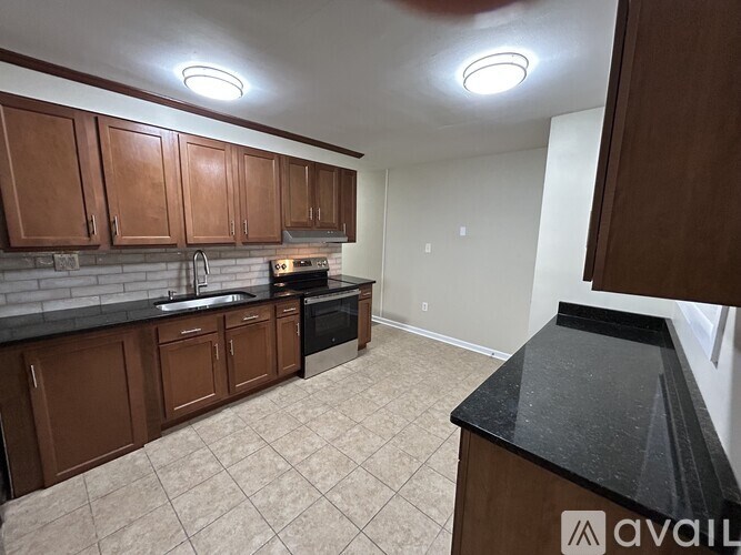 A kitchen with brown cabinets and a black countertop.