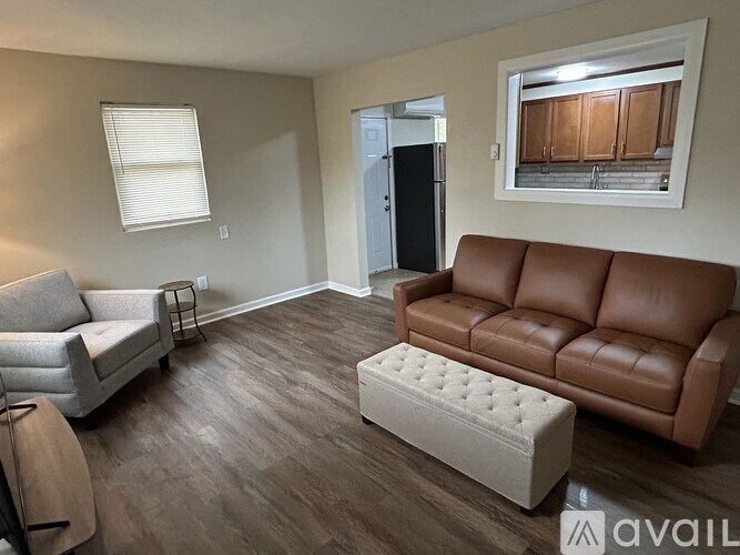 A living room with a brown leather couch and a white ottoman.
