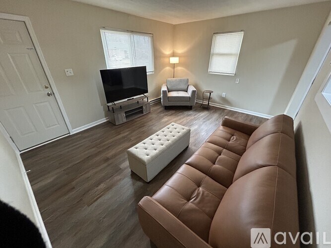 A living room with a brown leather couch and a white ottoman.