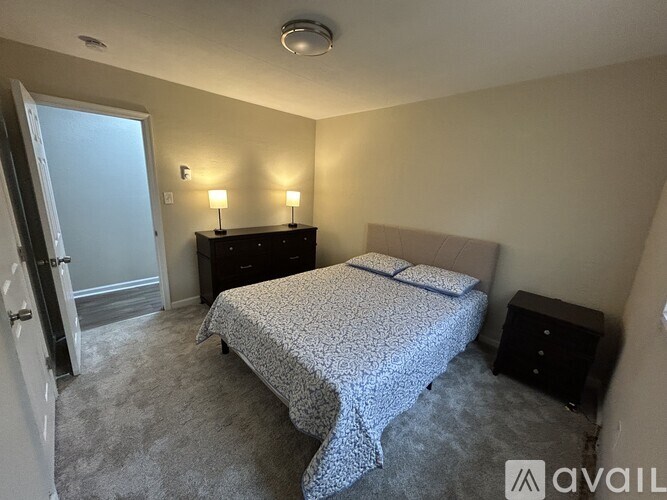 A bedroom with a bed, nightstand, and two lamps.